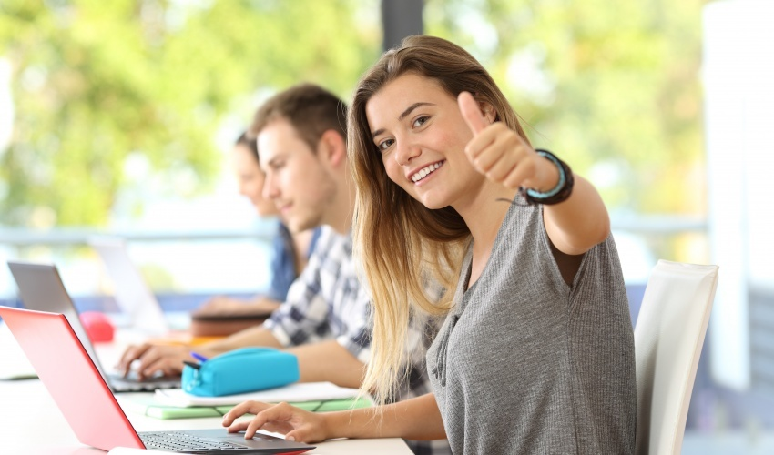A student in a classroom giving a thumbs up.
